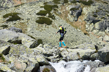 middle age man running on the trail above the waterfall in high mountains scenery