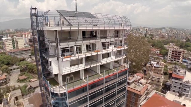 Office building under construction in Kathmandu drone footage. Solar panels and antenna on the roof.