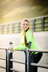 Sporty young woman on beach during summer. Fit female in sportswear is smiling on beach. Runner is exercising in nature on sunny day.