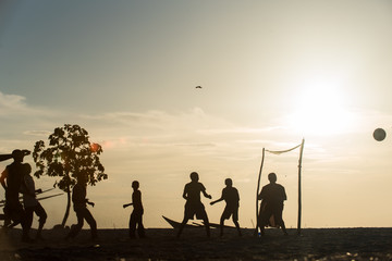 Locals playing football at sunset on tropical island