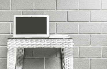 Closeup computer on blurred wood weave table and brown brick wall texture background , beautiful work place interior of house concept in black and white tone