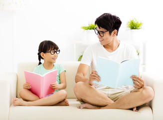 father and daughter studying together on sofa