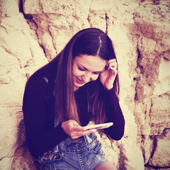 Long-haired cheerful female university student using cell phone