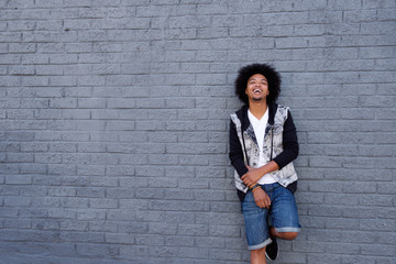 Cool young man with afro leaning against wall