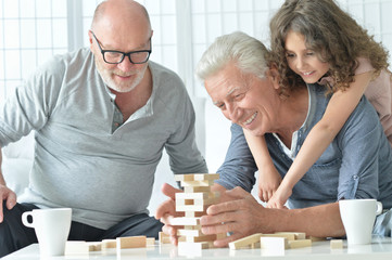 senior men and granddaughter with  board game