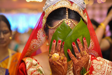 Bengali bride hiding her face with betel leaf also called paan. Hiding with paan leaf by the bride...