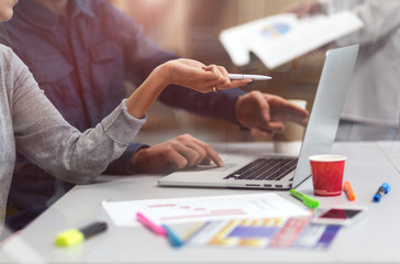 Throw the Window Image of young Business Team discussing Project at Computer at Modern Office Environment many printed Charts on Table