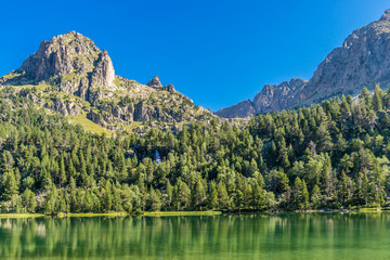Mountains and reflections on waters in St.Maurici National Park (Catalonia, Spain).