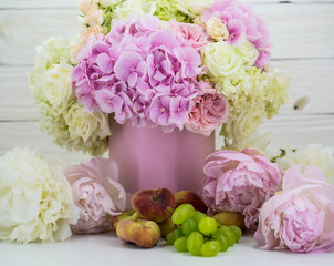 beautiful peonies in the pink box with fruits on wooden background