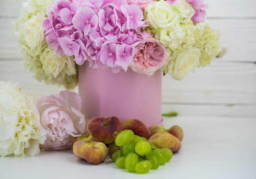 beautiful peonies in the pink box with fruits on wooden background
