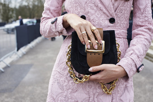 Mid section crop of woman in a pink coat holding a handbag