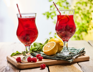 On wooden boards are ice cold beverage two glasses with red berries lemon cocktail . Alcohol country cocktail beverage number ninety seven with leaf mint. Outdoor cocktail .
