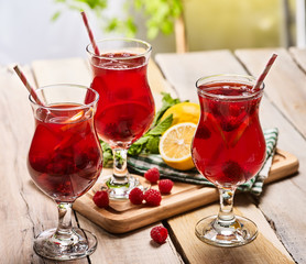 On wooden boards is ice cold beverage glass with red raspberry lemon cocktail . Alcohol country cocktail beverage number ninety eight with mint. Cocktail on outdoor.