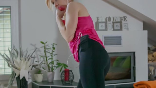 This young lady is working out with light weights and music and headphones. She is doing a tae bo. Close-up shot.
