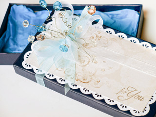 Handmade gift box decorated with blue and white gems, white lace and stamped paper