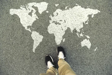 Foto op Plexiglas World map on an asphalt road. Top view of the legs and shoes. POV © leonidkos