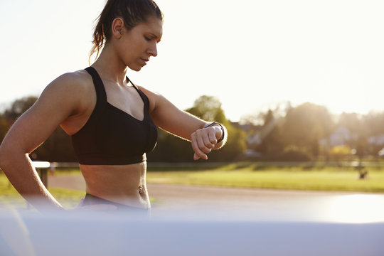 Young Woman Checks Activity Tracker During Outdoor Exercise