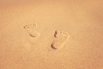 Fototapeta na wymiar stamp of feet on sand on the beach with sunshine in the morning,