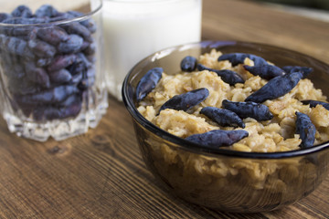 oatmeal with berries honeysuckle and drinking yoghurt on the background of old wooden planks