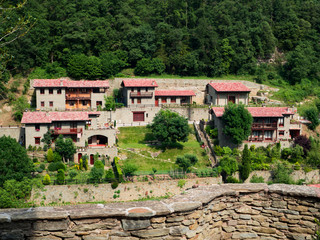 Vista del paisaje urbano con casas al fondo detrás de un muro de piedra desde la parte alta de Rupit, pueblo medieval de Osona Barcelona, verano de 2016.