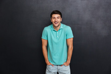 Cheerful excited young man standing with hands in pockets