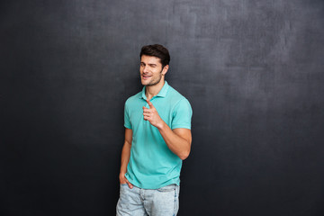 Handsome young man pointing at camera over black background