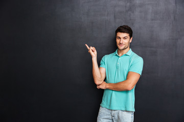 Confident man in blue t-shirt standing and pointing away