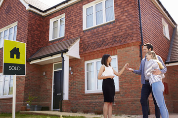 Obraz premium Young Couple Collecting Keys To New Home From Realtor