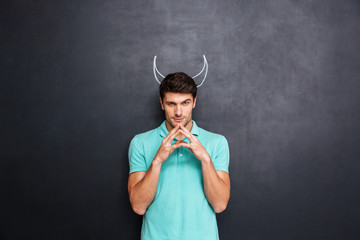 Serious man playing role of devil standing over blackboard background