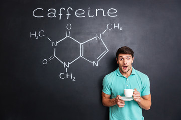 Surprised student drinking coffee over drawn structure of caffeine molecule