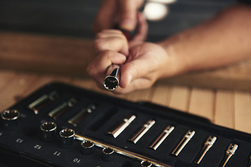 Close-up of mechanic hands changing socket wrench over toolbox. Concept of repair and diy. 