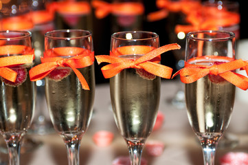 Sparkling wine with raspberry, ribbon decorated champagne glasses