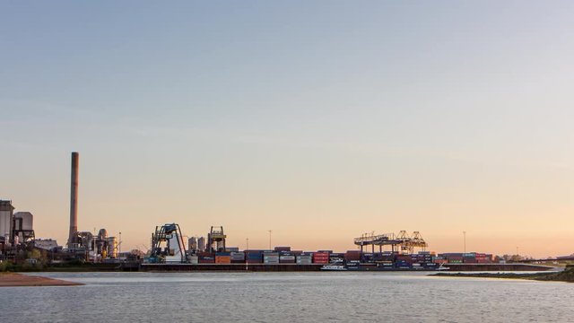 Ship loading containers at automated container terminal along a busy river, 4K time lapse