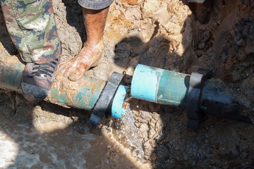 plumber workers repair pipe water main broken, tube underground water on road.