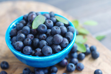 Berries of ripe juicy bilberry in a blue small  plate on a wooden table.