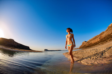beautiful sexy woman dressed in bikini walking on the beach along the sea front