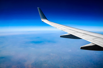 Wing of airplane flying above the clouds in the sky