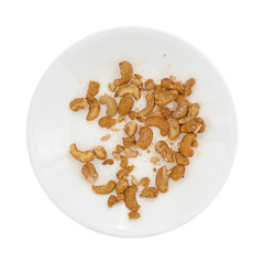 Pieces of honey roasted cashews on a white plate top view.