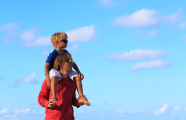 Father and little son on shoulders at sky