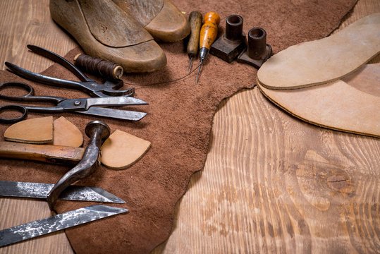 Set of leather craft tools on wooden background. Workplace for shoemaker.