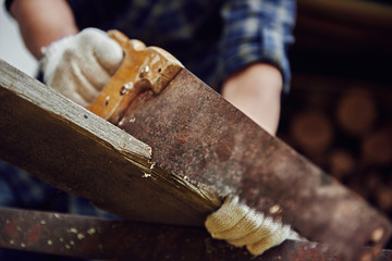 Close-up of woodworker sawing plank outdoor. Concept of construction and equipment. 