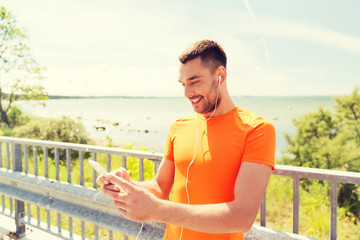 smiling young man with smartphone and earphones