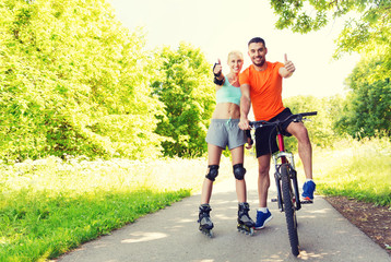 couple on rollerblades and bike showing thumbs up