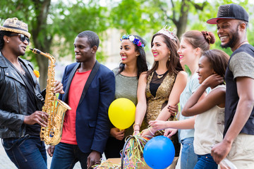 Straßenkünstler spielt Saxophon für eine multiethnische Party Gruppe junger Frauen auf Jungesellinnenabschied