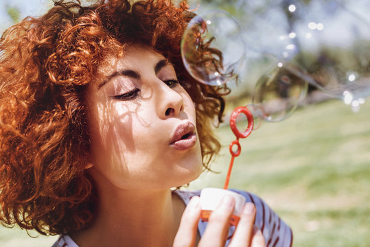 Beautiful young woman blowing bubbles in a park