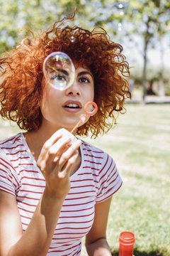 Beautiful young woman blowing bubbles in a park