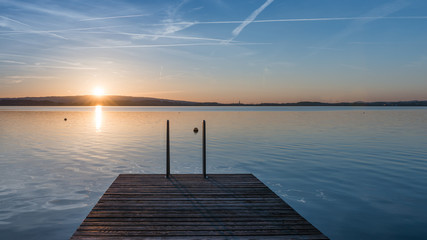 Naklejka na ściany i meble Jump. Relaxing quiet evening on the lake. Setting sun is reflected in water. Switzerland.