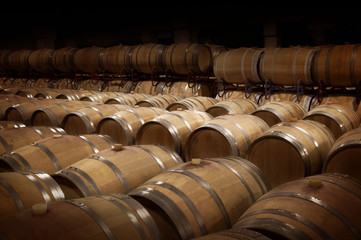 Wooden wine casks in wine cellar. Warm and dark ambiance.