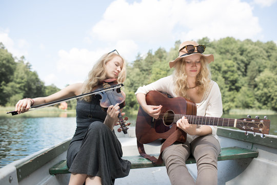 Cheerful Friends Having Fun Playing Music on a Rowboat