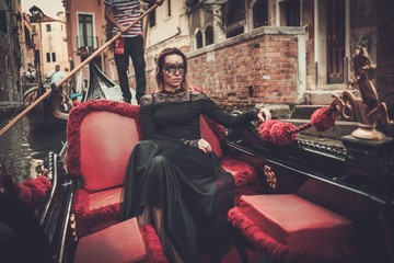Beautiful woman in black dress with carnaval mask riding on gondola.  - obrazy, fototapety, plakaty
